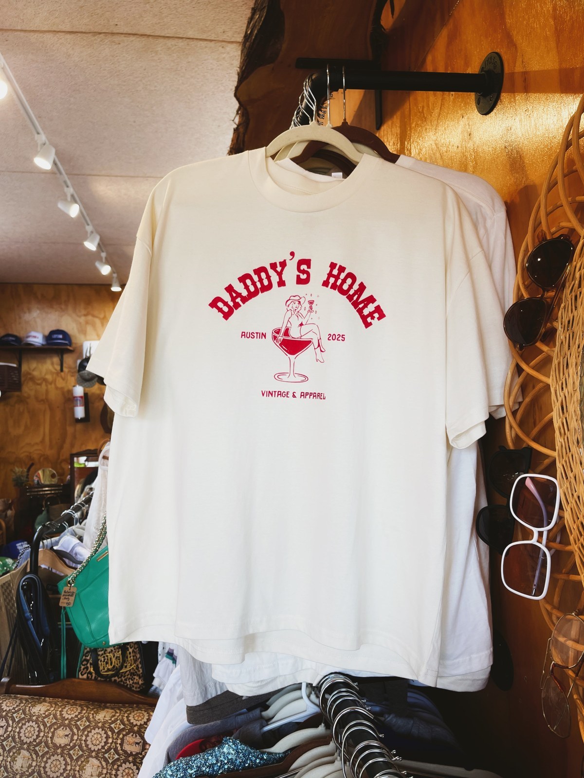 The Oversized Martini Logo Tee hanging on a brick wall