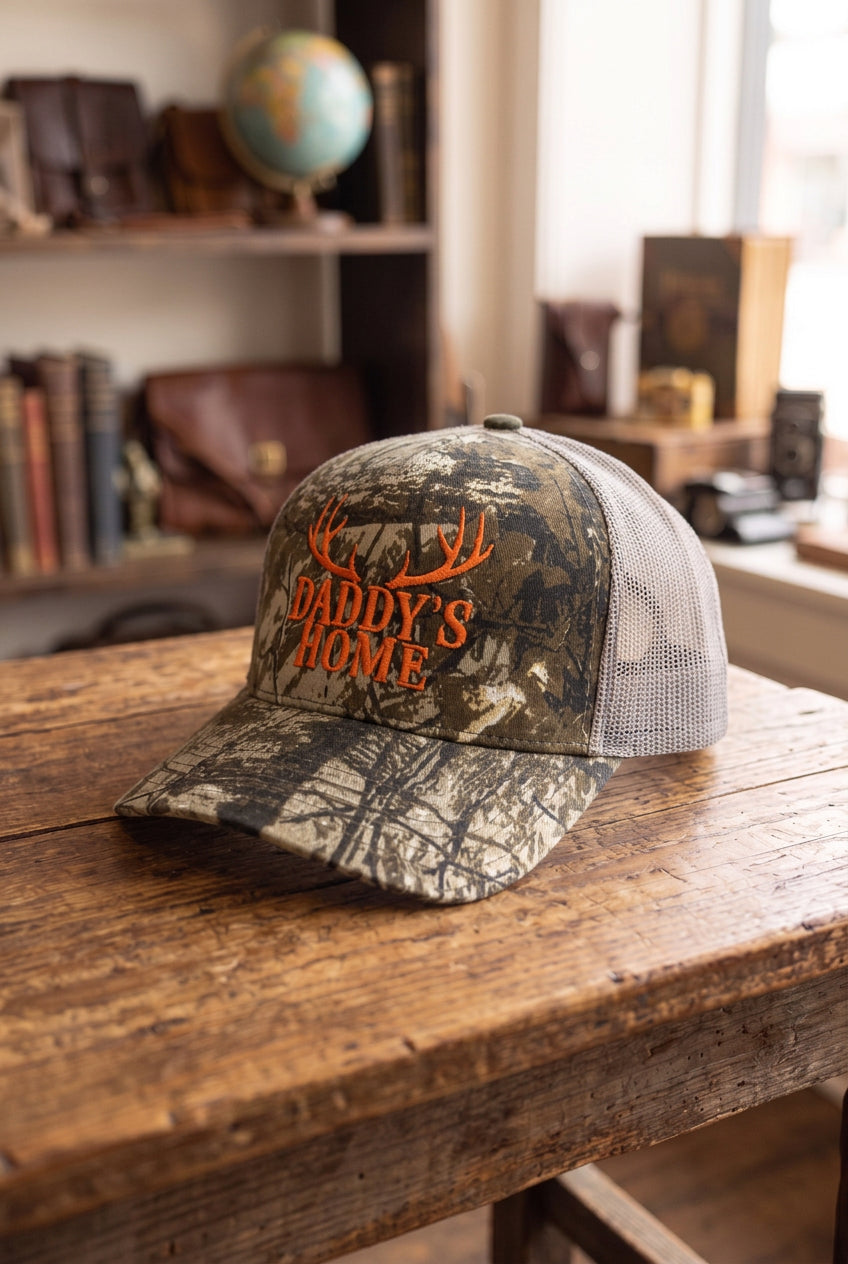 DADDY'S HOME embroidered camo trucker hat, angled view showing grey mesh back