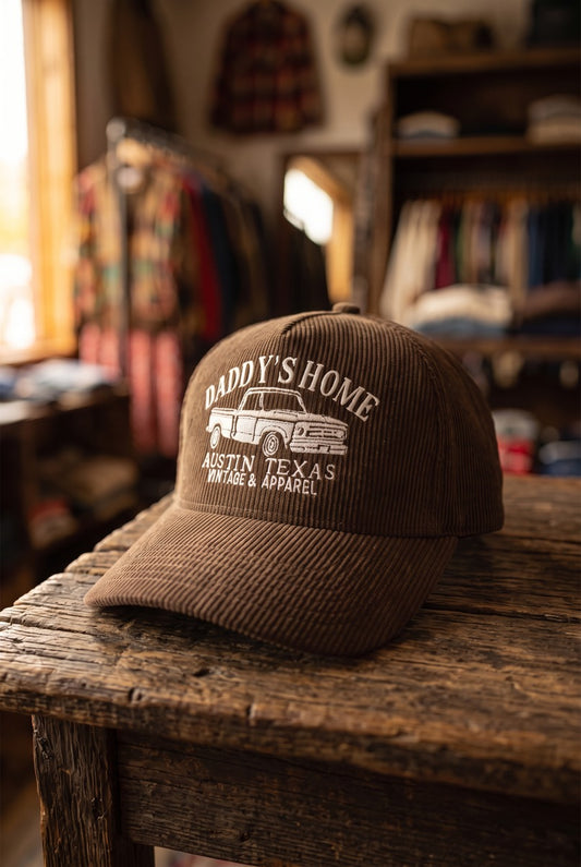 Brown embroidered Daddy's Home hat with solid corduroy crown on rustic wooden table