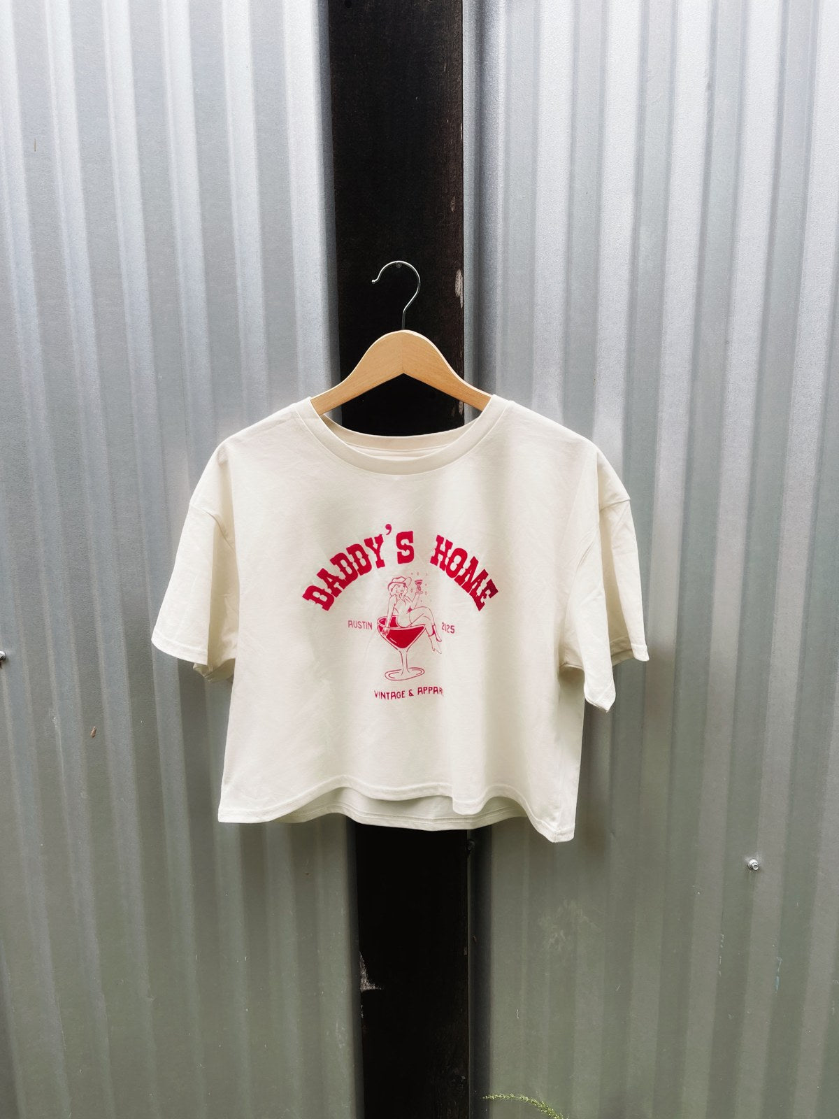 The Cropped Martini Logo Tee hanging on a wall